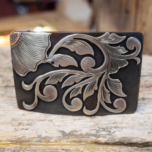 Decorative leather belt buckle with floral patterns on a wooden surface