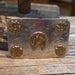 Metal belt buckle with floral designs and a horse head on a wooden surface